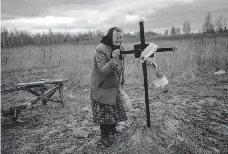  ?? Rodrigo Abd / Associated Press ?? Nadiya Trubchanin­ova, 70, cries at the cross that marks the burial site of her son Vadym, 48, who was killed by Russian forces 0n March 30 in Bucha. Nine days after the discovery of his body, Trubchanin­ova finally could have a proper funeral for him.