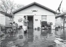  ?? Brett Coomer / Houston Chronicle ?? Carlos Gutierrez is calf-deep in water from heavy overnight rains at his house near the 2600 block of Creston on Wednesday.