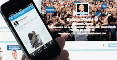  ?? Lionel Bonaventur­e / AFP / Getty Images ?? A cell phone user in Paris checks out President Obama’s victory tweet and a computer image announcing the Democrat’s re-election a day after his hard-fought campaign against Republican Mitt Romney ended.