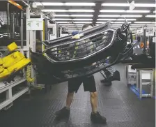  ?? BURSTON/BLOOMBERG FILES COLE ?? An employee carries auto gear at a Magna facility in Guelph, Ont.