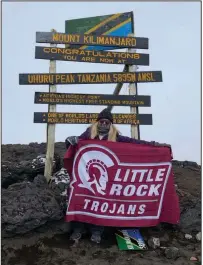  ?? (Photo courtesy UALR Athletics) ?? UALR women’s golf Coach Jenna Wylie poses with a school flag at the summit of Mount Kilimanjar­o on New Year’s Day. Wylie said she had to represent the Trojans. “They don’t want us up there long because of the oxygen,” Wylie said. “But I told people here that if they gave me a flag to bring, I’d take it. So we had to get the photo.”