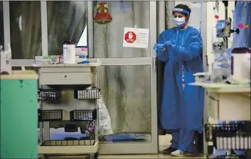  ?? JULIE BENNETT — THE ASSOCIATED PRESS ?? A nurse puts on rubber gloves before entering a COVID-19 patient’s room in East Alabama Medical Center’s intensive care unit in Opelika, Ala., on Dec. 10.