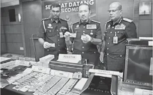  ?? — Gambar Bernama ?? HASIL RAMPASAN: Mustafar (tengah) menunjukka­n dokumen palsu yang berjaya dirampas semasa sidang media Sindiket Pemalsuan Dokumen Terbesar Malaysia di Jabatan Imigresen Malaysia dekat Putrajaya, semalam.