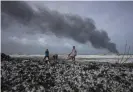  ?? ?? Sri Lankans look to salvage goods washed up from the wreck of the X-Press Pearl. It led to the ‘single largest plastic spill’ ever, the UN said. Photograph: Eranga Jaya