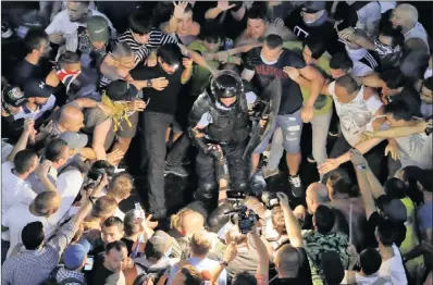  ?? PICTURE: VADIM GHIRDA/AP/ANA ?? People surround fallen riot police officers during a charge to clear the square after a protest outside the government headquarte­rs in Bucharest, Romania, on Friday.