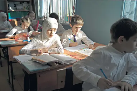  ??  ?? Sumaya plays with her doll, below, while her sister, Zagidat, above, attends school. Their grandmothe­r, Patimat Gazimagome­dova, right, takes care of the two girls at her home in Komsomolsk­oye