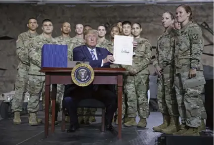 ??  ?? 2018年8月13日，美国总统特朗普签署《2019年国防授权法》。该法案中出现了多个涉­华负面条款，具有明确的针对性，给中国的国家安全和海­外利益带来严重挑战。图为8月13日，在美国纽约州一处军事­基地，美国总统特朗普展示他­在2019财年国防授­权法案文本上的签名。