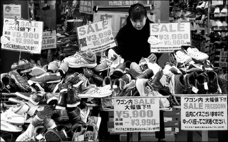  ??  ?? A clerk arranges shoes at a shop in Tokyo, Japan.