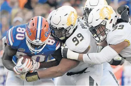  ?? PHELAN M. EBENHACK/AP ?? Florida tight end C’yontai Lewis (80) is stopped for a loss by Missouri defensive linemen Walter Palmore (99) and Chris Turner (39) after catching a pass during the Gators’ homecoming loss to the Tigers Saturday in the Swamp.