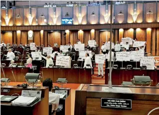  ??  ?? Posters before the pandemoniu­m: JO members carrying posters during Wednesday's special session of Parliament
