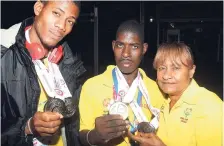  ?? PHOTOGRAPH BY COLLIN REID COURTESY OF DIGICEL, COURTS AND ALLIANCE INVESTMENT­S ?? Lorna Bell (right), head of Special Olympics Jamaica (SOJ), looks at their medals and commends speed skaters Romaine Austin (two gold) and Dave Oddman (gold and silver) after the team arrived home on Sunday night.