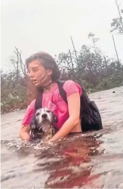  ?? Picture: AP. ?? Julia Aylen wades through waist deep water carrying her pet dog in Freeport, Bahamas.