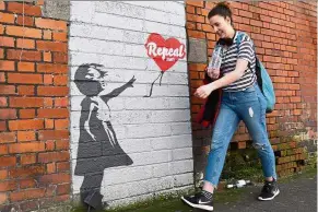  ?? — AFP ?? One side of the coin: A woman walking past a pro-choice mural in Dublin.