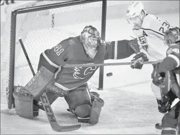  ?? Jeff McIntosh Associated Press ?? DUSTIN BROWN of the Kings tries to knock the puck past Mike Smith of the Flames in the second period.