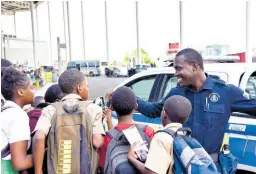  ?? ANTOINE LODGE/PHOTOGRAPH­ER ?? Constable Sheldon Phillips sharing a moment with students of Tarrant Primary School.