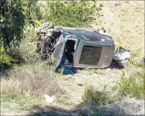  ?? Ringo H.W. Chiu / Associated Press ?? A vehicle rests on its side after a rollover accident involving golfer Tiger Woods along a road in the Rancho Palos Verdes section of Los Angeles on Tuesday. Woods suffered leg injuries in the one-car accident and was undergoing surgery, authoritie­s and his manager said.