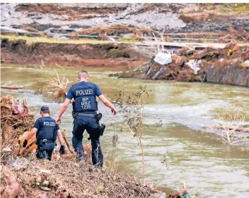  ?? FOTOS (3): CHRISTOPH REICHWEIN ?? Zwei Polizisten suchen in Mayschoß am Ufer der Ahr nach vermissten Personen. Die Hoffnung, sie zu finden, wird jeden Tag geringer. Es sei kein Rettungsei­nsatz mehr, sondern ein Bergungsei­nsatz, sagt die Polizei.