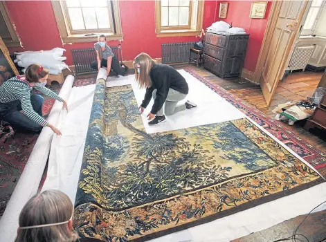  ??  ?? LABOUR OF LOVE: National Trust staff unroll a restored tapestry ready to rehang it at Dyrham Park near Bath.