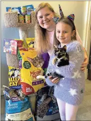  ?? / Murielle Cunnyngham ?? Hadley Cunnyngham, who is holding Clove the cat who is available for adoption at Petland, is a 6-year-old cat lover who decided to ask her friends to bring cat food to her birthday party instead of toys. She took the 73 pounds of dry cat food and 18 cans of wet food to Floyd Felines &amp; Friends where volunteer and family friend Sarah Hallstein accepted the donation.