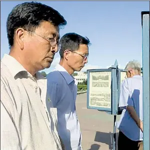  ?? AP ?? North Korean men read newspapers displayed on the street Friday in Pyongyang, where, despite tensions and talk of war, life in the capital remained calm.