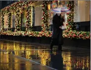  ?? (AP/Mark Lennihan) ?? A shopper walks past holiday window displays Monday in New York. Online shoppers in the U.S. spent up to $10.8 billion Monday, according to a revised estimate from Adobe Inc.