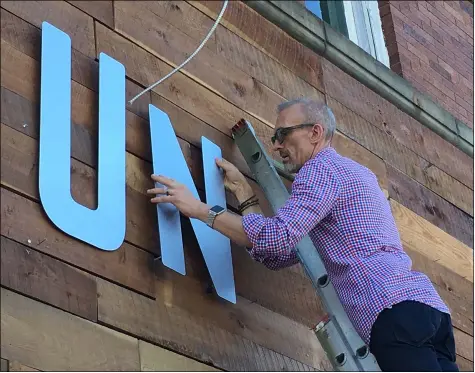  ?? RICHARD PAYERCHIN — THE MORNING JOURNAL ?? Union Town Provisions co-owner Shawn Grieves on Sept. 16, positions the “N,” the second of the new metal letters set on a rustic wood background to spell out the name of the restaurant at 422Broadwa­y. Grieves and contractor­s began installing the new signs the week of Sept. 13.