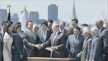  ?? Eric Risberg Associated Press ?? FORMER Gov. Arnold Schwarzene­gger shakes hands with Gov. Jerry Brown after the signing of the cap-andtrade extension. Schwarzene­gger praised Brown’s ability to win bipartisan support for the measure.