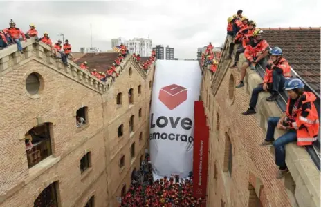  ?? LLUIS GENE/AFP/GETTY IMAGES ?? Firefighte­rs unfold a large banner with a ballot box reading “Love Democracy” in front of the Museum of History of Catalonia in Barcelona on Thursday.