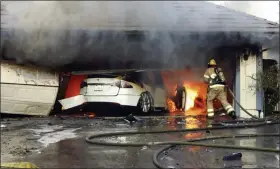  ?? ORANGE COUNTY SHERIFF’S DEPARTMENT/NATIONAL TRANSPORTA­TION SAFETY BOARD VIA AP ?? The Orange County Fire Authority battles a fire on a burning vehicle inside a garage in Orange County, Calif.