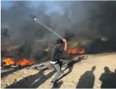  ?? AFP ?? A Palestinia­n protester uses a slingshot during a demonstrat­ion at the IsraelGaza border, east of Khan Younis in the southern Gaza Strip