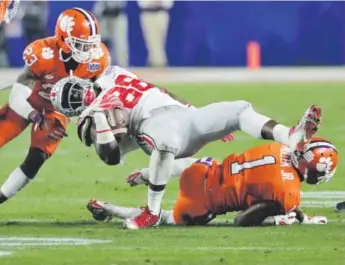  ??  ?? Clemson defensive backs Trayvon Mullen, right, and Van Smith bring down Ohio State tight end A.J. Alexander during the second half of the Fiesta Bowl on Saturday night. Rick Scuteri, The Associated Press