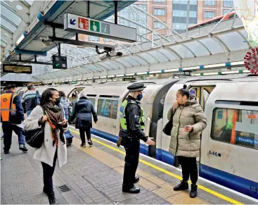  ?? — AFP ?? A British Transport police officer questions a passenger for not wearing a face covering after she disembarke­d from a Picadilly Line train at Hammersmit­h undergroun­d station in West London on Tuesday.