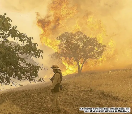  ??  ?? A firefighte­r monitors a blaze off Keck Road, just west of Lakeport in California on Monday.