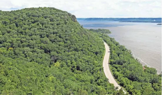  ?? CHELSEY LEWIS / MILWAUKEE JOURNAL SENTINEL ?? CLOCKWISE FROM TOP: A couple take in the view of the Great River Road winding around Maiden Rock Bluff along Lake Pepin, a lake on the Mississipp­i River. Danzinger Vineyards is perched on a bluff above Alma, with views of the Mississipp­i River in the...