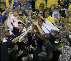  ?? BEN MARGOT — THE ASSOCIATED PRESS ?? Golden State Warriors players, coaches and owners hold up the Larry O’Brien NBA Championsh­ip Trophy after Game 5 of basketball’s NBA Finals between the Warriors and the Cleveland Cavaliers in Oakland Monday. The Warriors won 129-120 to win the NBA...