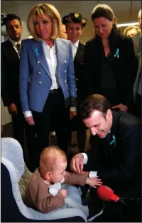  ?? The Associated Press ?? CATCHING UP: French President Emmanuel Macron plays with a baby as his wife Brigitte, left, and French Health Minister Agnes Buzyn look on Thursday during a visit to the Rouen hospital in Normandy.