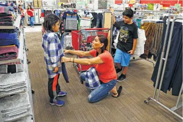  ?? Ronald Cortes / Contributo­r ?? Holly Videan shops for school clothes for Derek Contero, 7, as her other grandson Izaiah Contero, 10, watches.