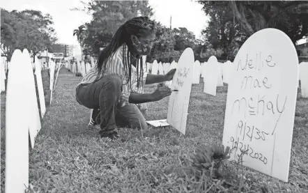  ?? LYNNE SLADKY/AP FILE ?? Joanna Moore writes a tribute to her cousin Wilton “Bud” Mitchell who died of COVID-19 at a symbolic cemetery created to remember and honor lives lost to the pandemic, in the Liberty City neighborho­od of Miami on Nov. 24. The U.S. death toll from COVID-19 has topped 600,000, even as the vaccinatio­n drive has drasticall­y slashed daily cases and deaths and allowed the country to emerge from the gloom.