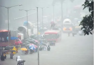  ?? — AFP photo ?? People wade along a flooded street during heavy rain showers in Mumbai.