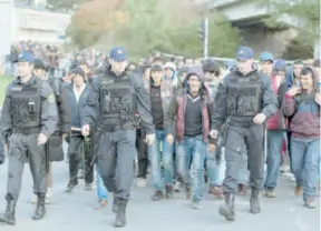  ??  ?? Escoltados por policías, refugiados llegan a territorio austriaco.