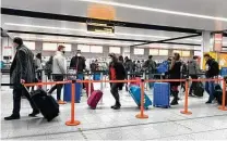  ?? Gareth Fuller / Associated Press ?? Passengers check in Sunday at Gatwick Airport south of London. The U.S. now requires travelers to test negative for the virus.