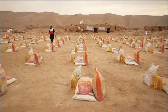  ?? (AP/Mstyslav Chernov) ?? A member of the Internatio­nal Federation of the Red Cross stands Dec. 13 among the food rations to be distribute­d to farmers suffering from drought in Sang-e-Atash, Afghanista­n.