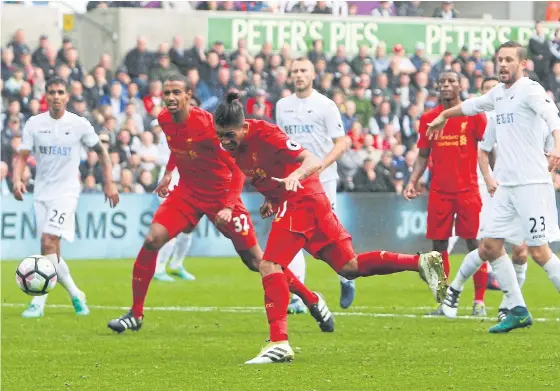  ??  ?? Liverpool’s Brazilian midfielder Roberto Firmino, centre, heads the ball to score their equaliser at the Liberty Stadium in Swansea.