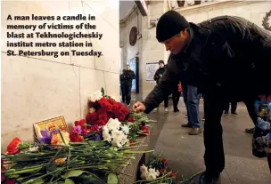  ??  ?? A man leaves a candle in memory of victims of the blast at Tekhnologi­cheskiy institut metro station in St. Petersburg on Tuesday.