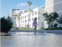  ?? LYNNE SLADKY/ASSOCIATED PRESS FILE PHOTO ?? A woman walks along a flooded street caused by a king tide in September 2019 in Miami Beach, Fla. A new federal report says the city, already seeing ‘nuisance’ floods, could by midcentury see floods that cause property damage, even on sunny days.