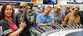  ?? KEN HERMAN / AMERICAN-STATESMAN ?? Attendees at NRA annual meeting in Dallas check out handguns on display in the exhibit hall.