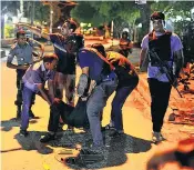  ??  ?? Residents and police officers help one of the injured as troops and the gunmen exchange fire on Friday night. The attack marks a major escalation in a campaign by militants in Bangladesh