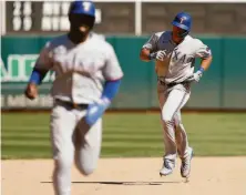  ?? Lachlan Cunningham / Getty Images ?? Texas’ DJ Peters rounds the bases behind Adolis Garcia after hitting a two-run home run off Sergio Romo in the eighth.