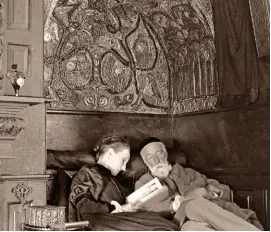  ??  ?? Mary reading to her husband George circa 1894-5 in a decorative nook, in what was known as the Red Room at Limnerslea­se.