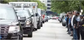  ?? ASHLEE REZIN GARCIA/SUN-TIMES ?? Officers lining the street outside the Cook County medical examiner’s office salute as the ambulance carrying the body of Dion Boyd passes.